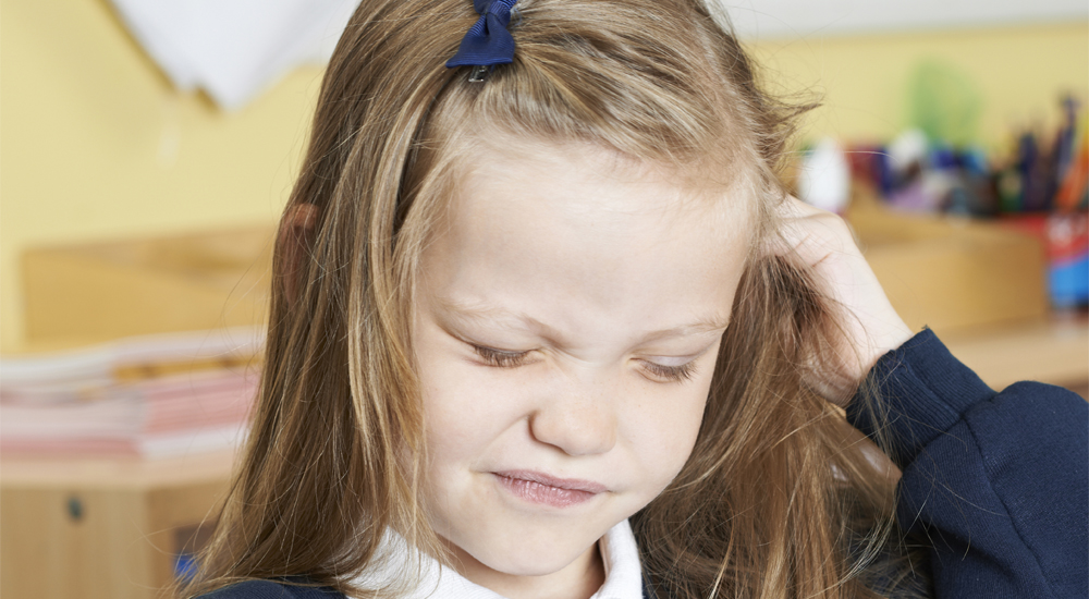 Fillette qui se gratte la tête à cause des poux en classe